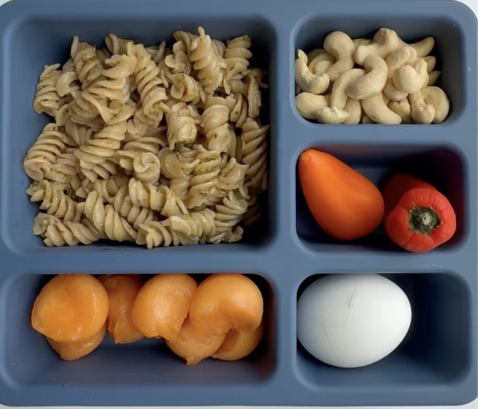lunch box meal with multigrain pasta, cashews, peppers, melon, and egg. perfect for a busy mom